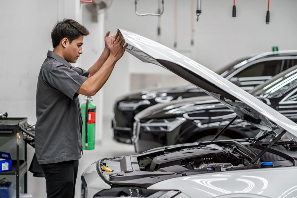 Asian mechanic Checking and Opening the car hood in maintainance